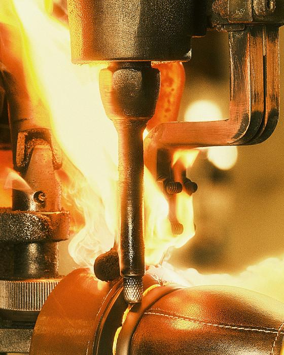 Heißes Messer fräst eine Nut ins Leder, Flammen flackern um das Werkzeug