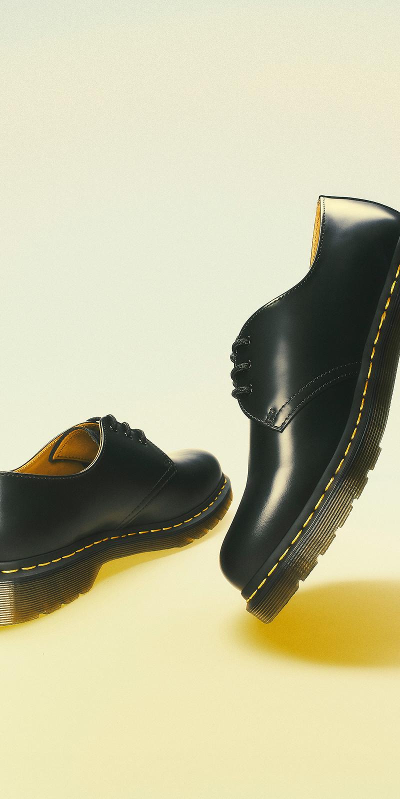 Zapatos de cordones en cuero liso negro con pespunte amarillo, uno inclinado