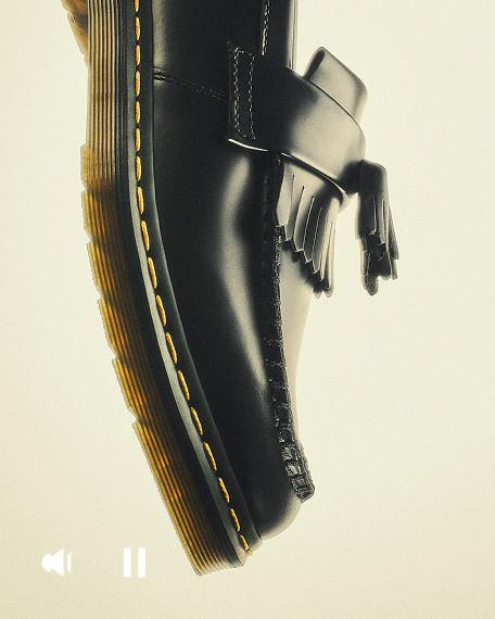 Close-up of black leather loafer with tassels, yellow welt stitching and grooved sole