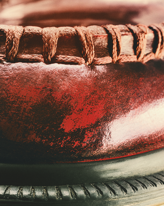 Close-up of red leather with a worn finish, tan laces and black grooved sole