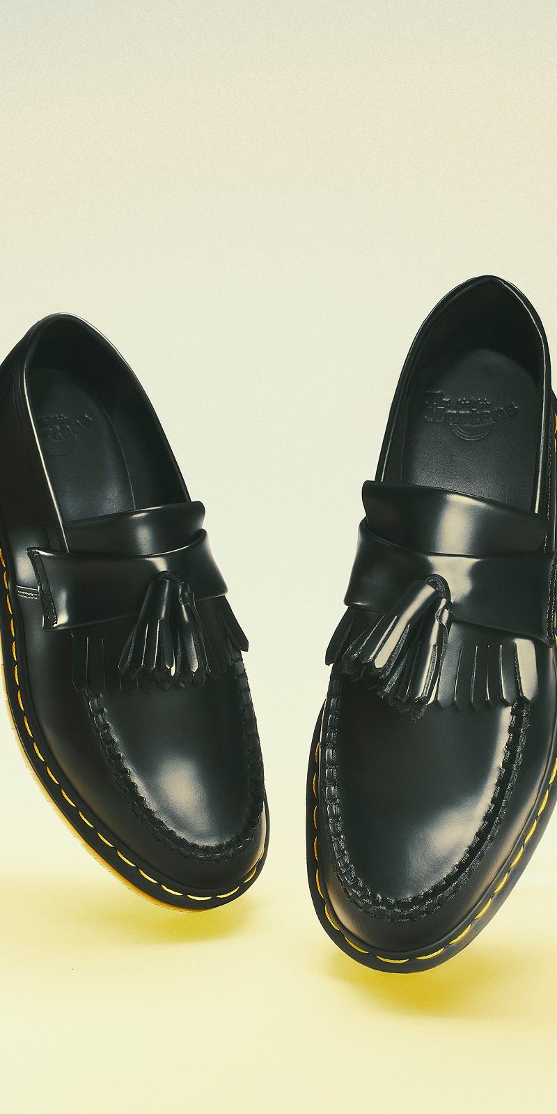 Mocasines negros de piel lisa con borlas y pespunte amarillo en la vira