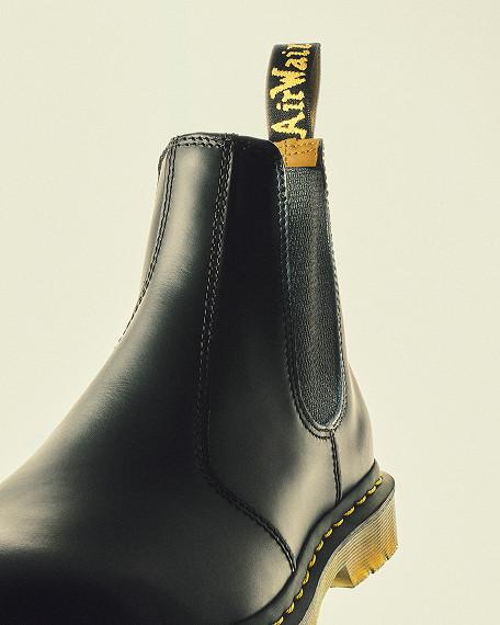 Nahaufnahme: schwarzer Chelsea-Boot aus Glattleder mit Gummieinsatz und gelber Schlaufe
