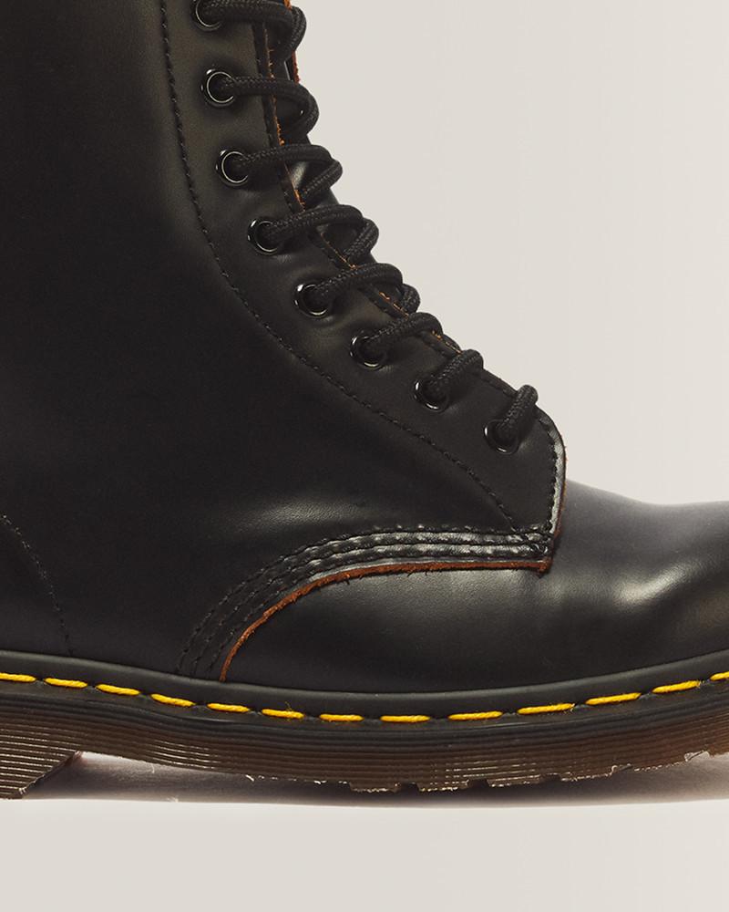 Gros plan sur une boots à lacets en cuir noir avec œillets métalliques et couture jaune