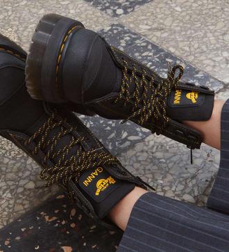 Dr. Martens x GANNI mustat kengät jalassa, keltamustat nauhat.