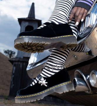 Chaussures noires Dr Martens avec chaussettes rayées et bracelet argenté.