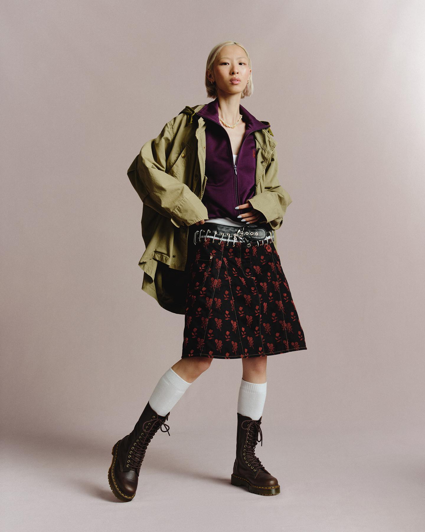 Model in dark brown lace-up boots, white socks and red floral skirt with khaki jacket