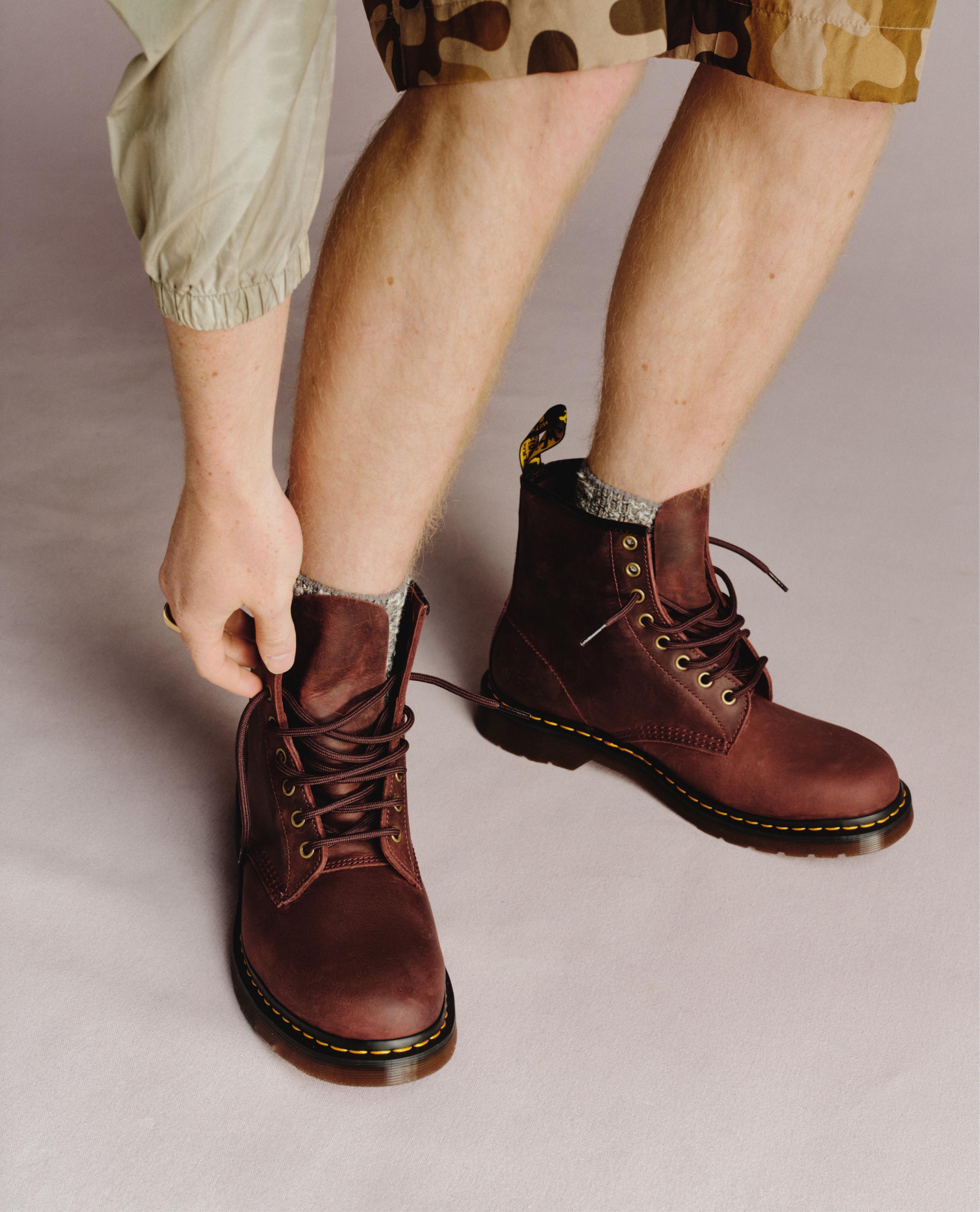 Oxblood leather lace-up ankle boots with yellow welt stitching, worn with grey socks