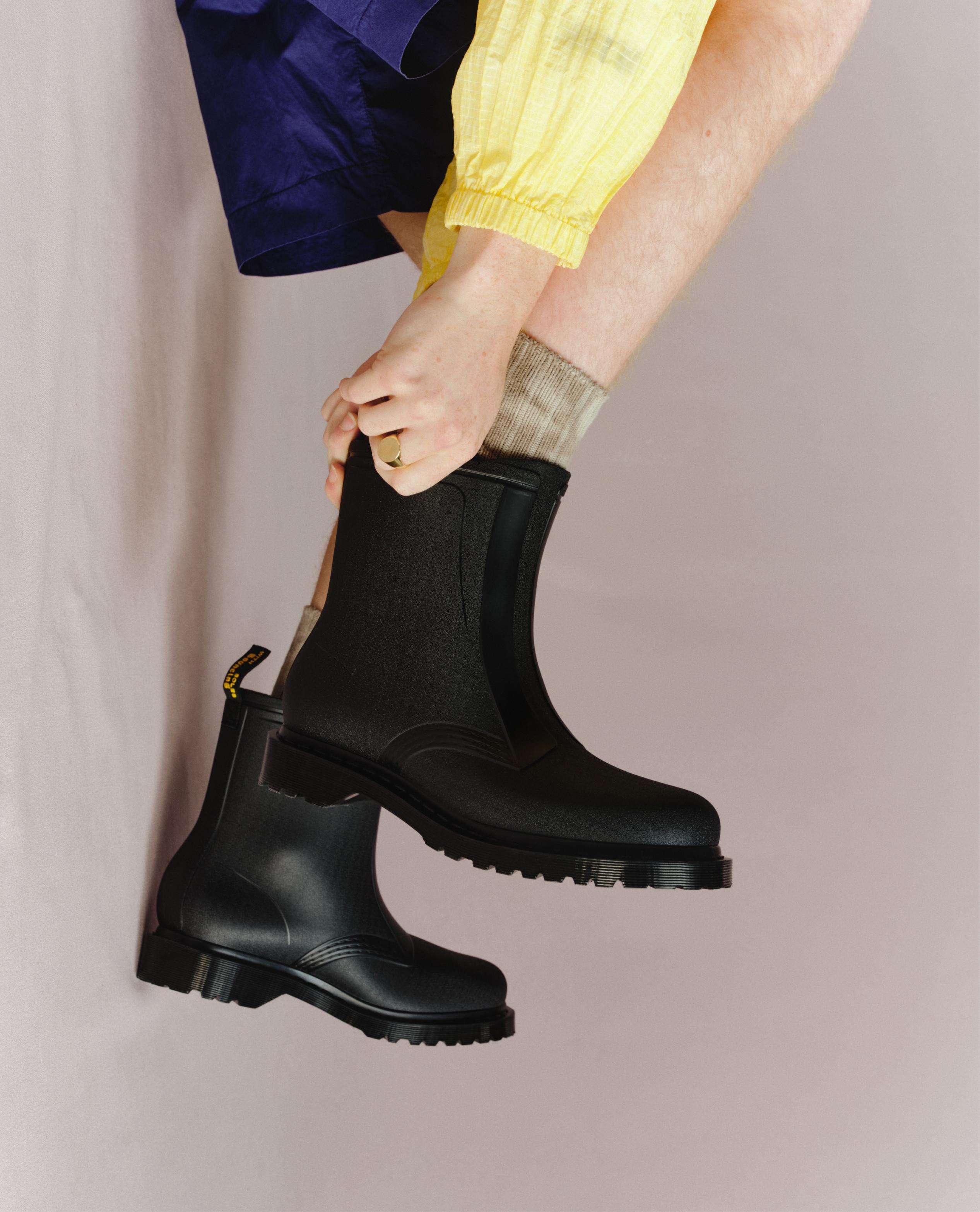 Black ankle Chelsea boots with chunky tread, worn with grey socks and bright yellow trousers