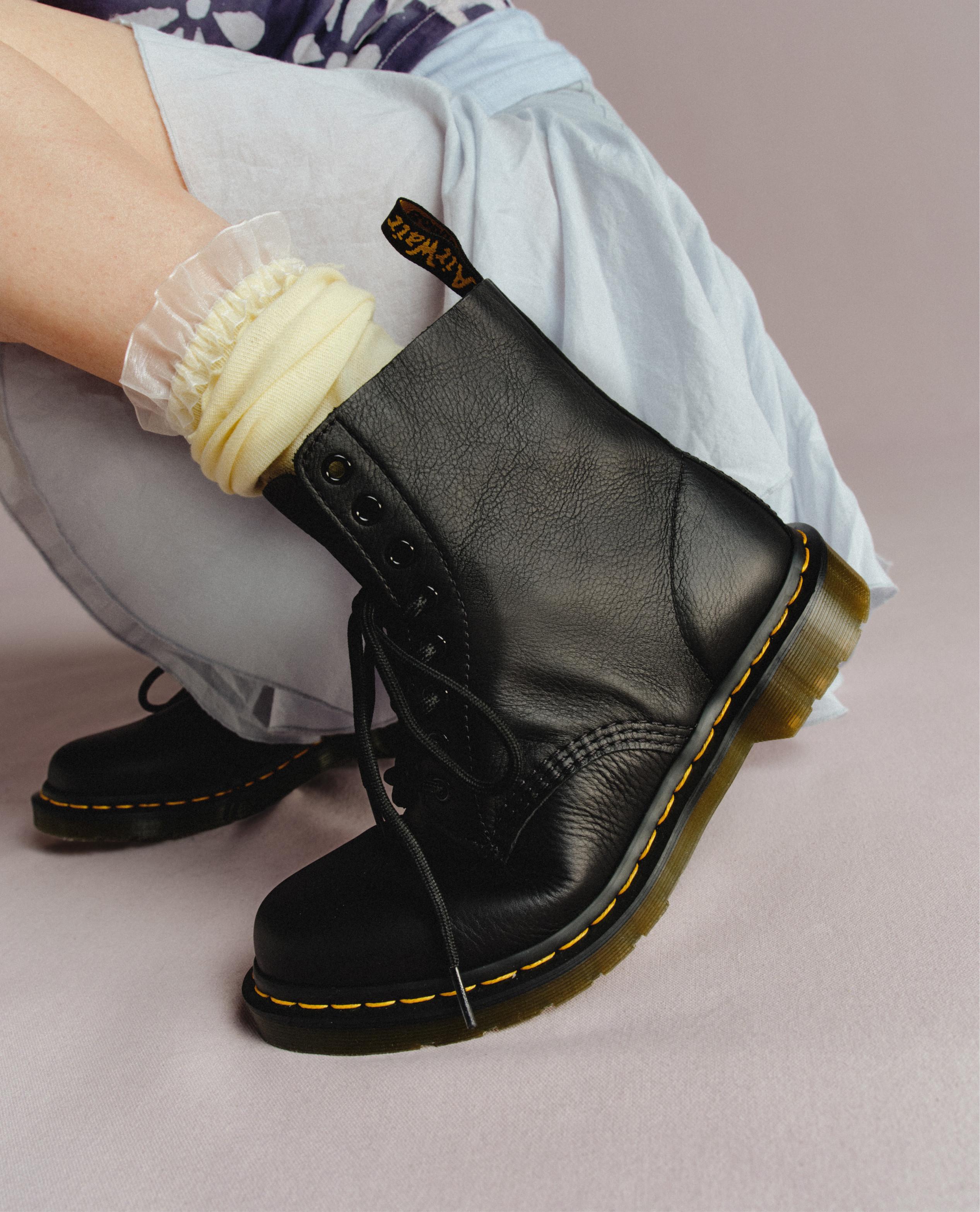 Black leather lace-up boots with yellow welt stitching, worn with ruffled socks