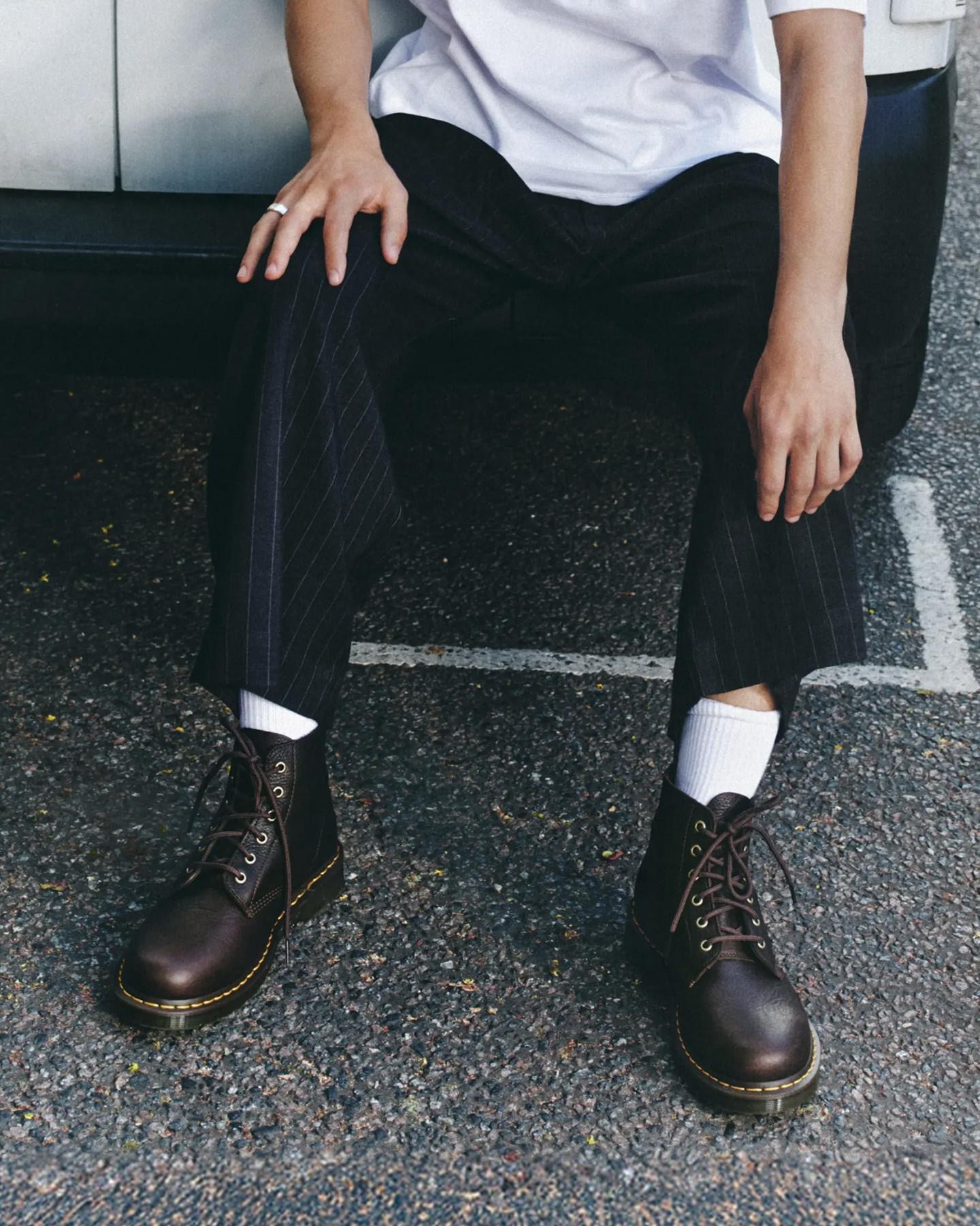 Dark brown leather lace-up boots with yellow welt stitching, worn with pinstripe trousers