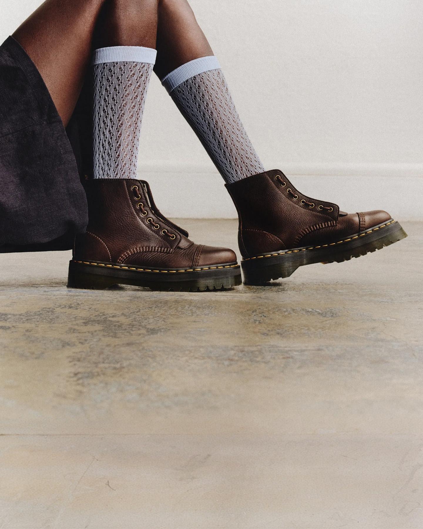 Dark brown leather lace-up boots with yellow welt stitching, worn with pale grey lace socks