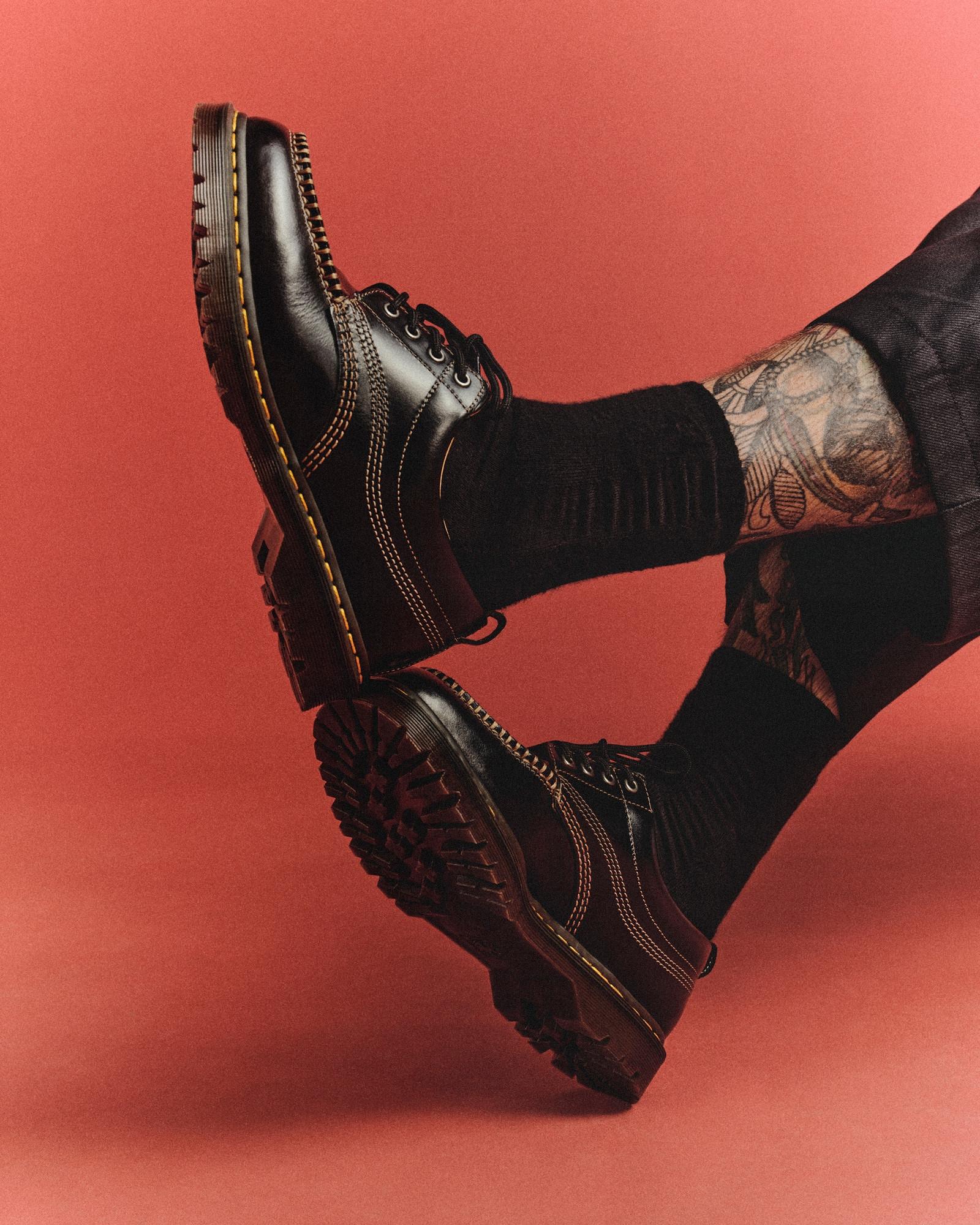 Black leather platform shoes with contrast stitching and yellow welt, worn with black socks