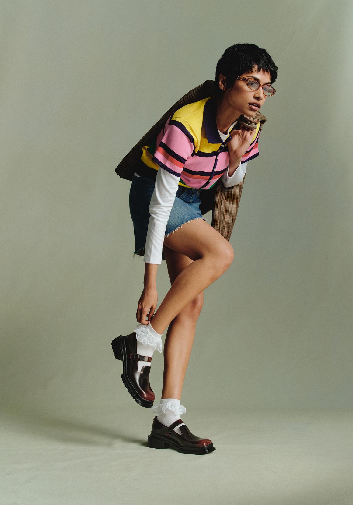 Person in burgundy leather Mary Jane shoes with ruffled white socks, lifting one heel
