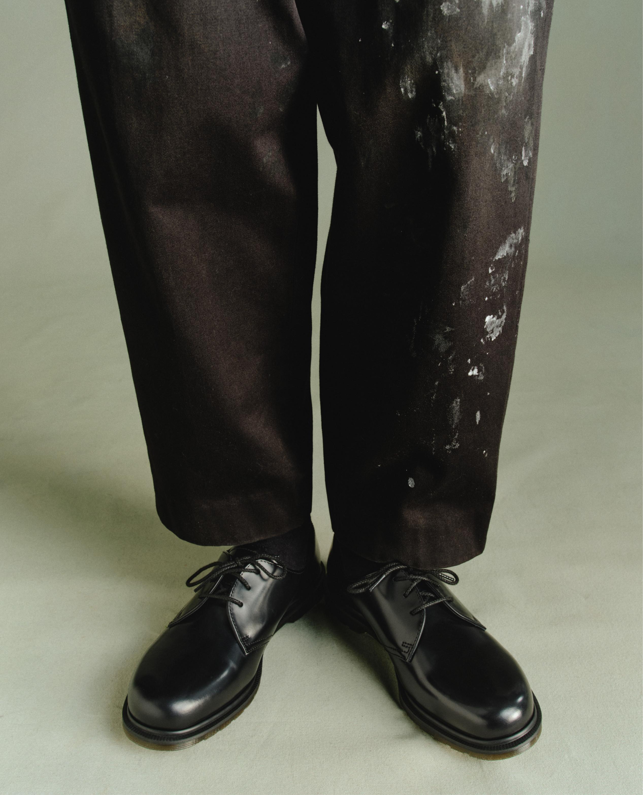 Zapatos negros de piel con cordones, con pantalón negro salpicado de pintura
