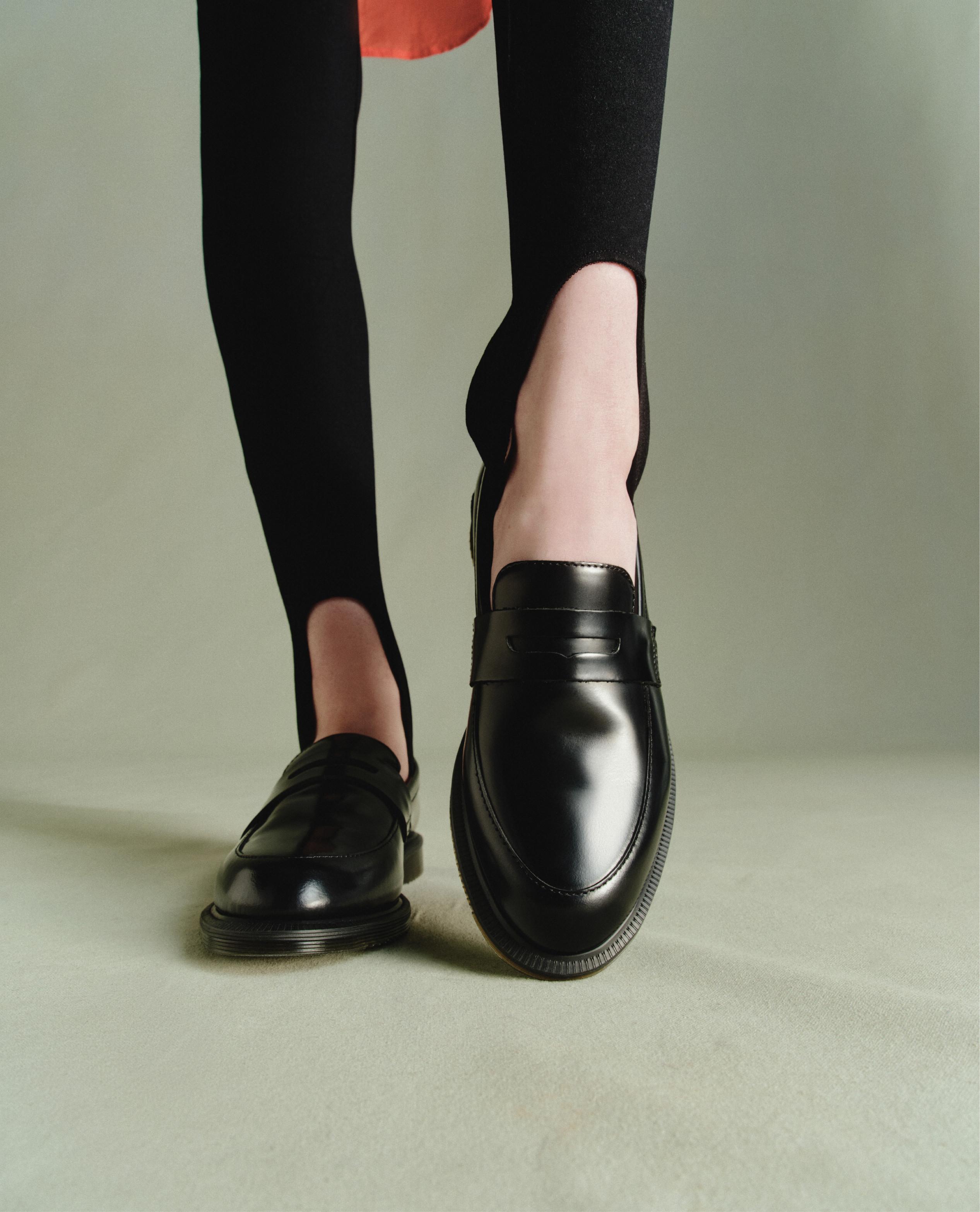 Mocasines de cuero negro pulido puestos con medias de estribo, primer plano
