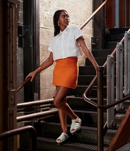 Summer outfit idea styling a button-up top and a colorful skirt with slide sandals
