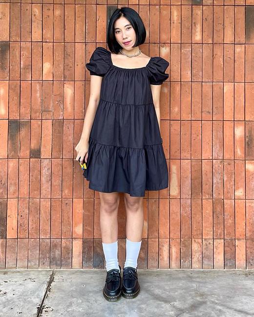A woman wearing a black dress with Dr. Martens loafers
