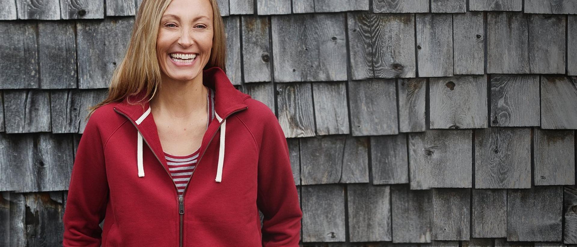 Woman wearing a red zip-up hoodie, smiling.