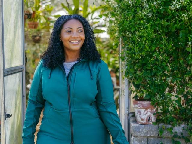 Woman in a greenhouse wearing a teal jacket