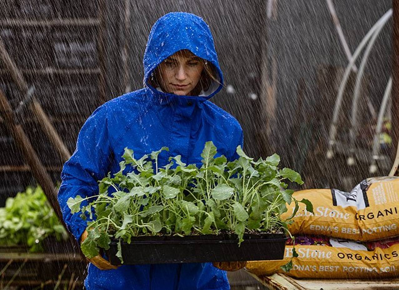 Woman carrying plants in the rain wearing No-Rainer jacket