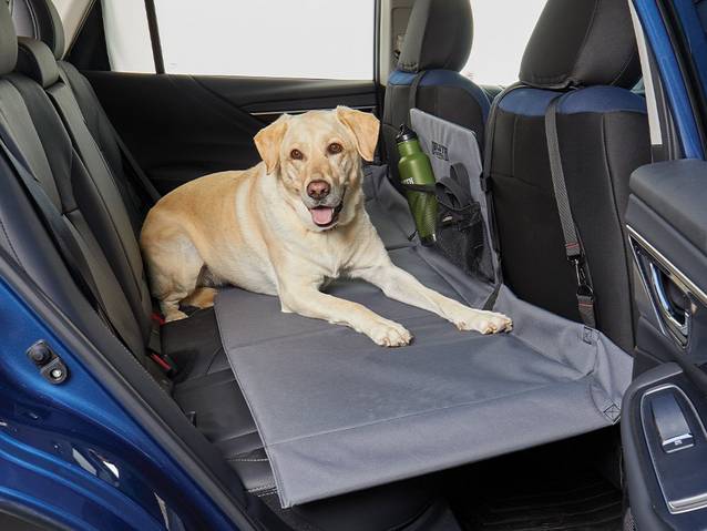 happy dog laying on a duluth seat cover in the back seat of a car