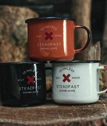 A stack of three enamelware mugs, one black, one orange, one white