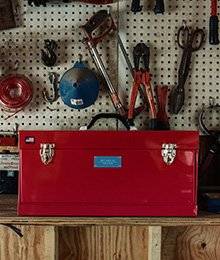 A red Best Made tool box sits on a workshop bench