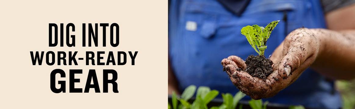 Dig into work-ready gear. An close up image of a woman in blue overalls holding a tiny plant in her dirt-covered hand.