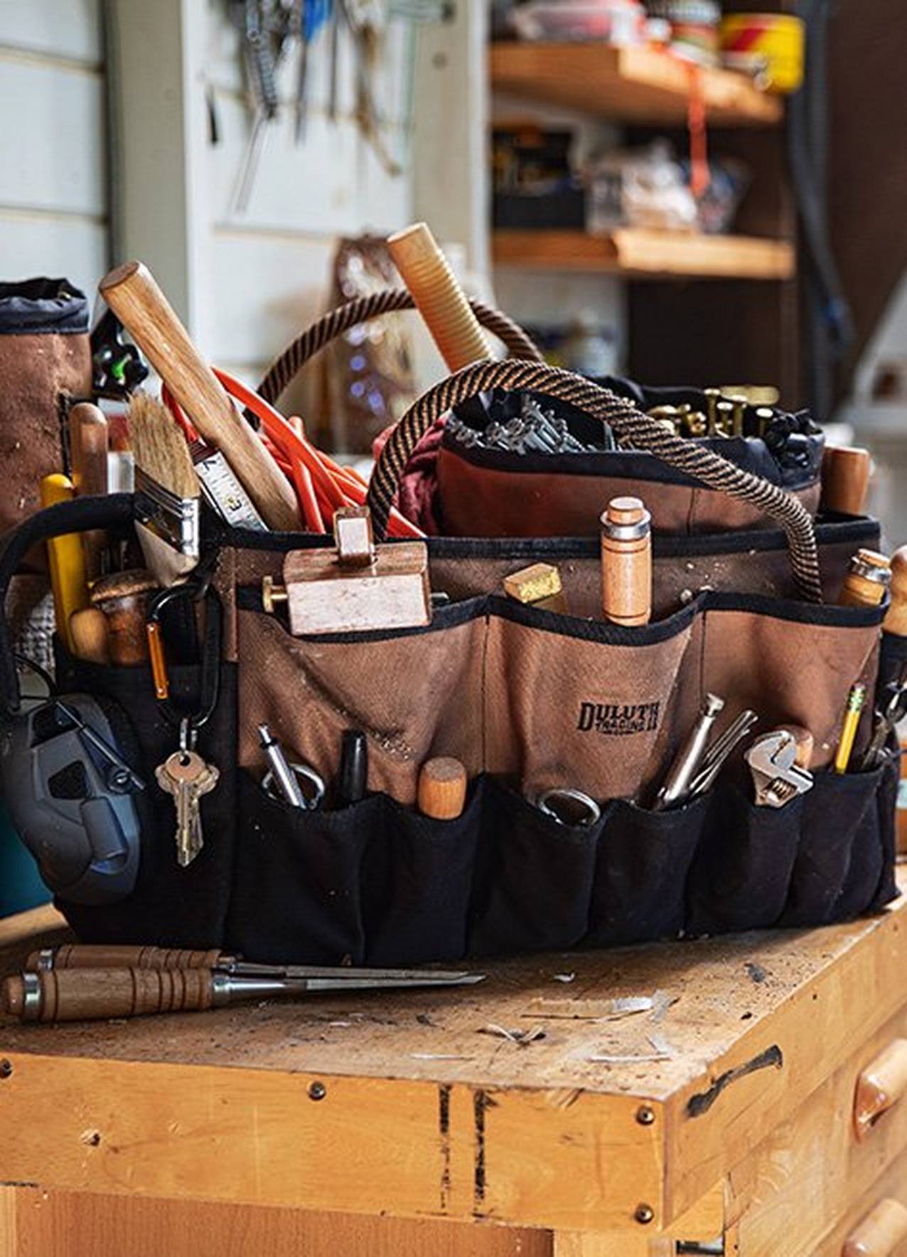 A fire hose toolbag sits in a workshop with it's pockets full of tools.