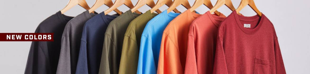 Headline: New Colors. Colored t-shirts hanging on wooden hangers