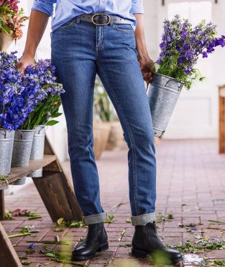 Woman wearing blue jeans, carrying flowers.