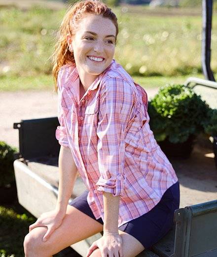 Woman wearing a pink plaid button-down shirt.