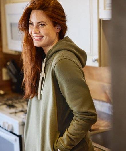 Woman wearing a green hooded sweatshirt.