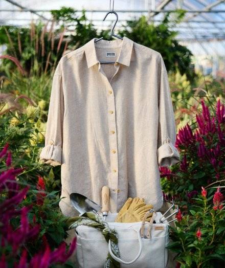 Women's tan button-down shirt hanging in a greenhouse.