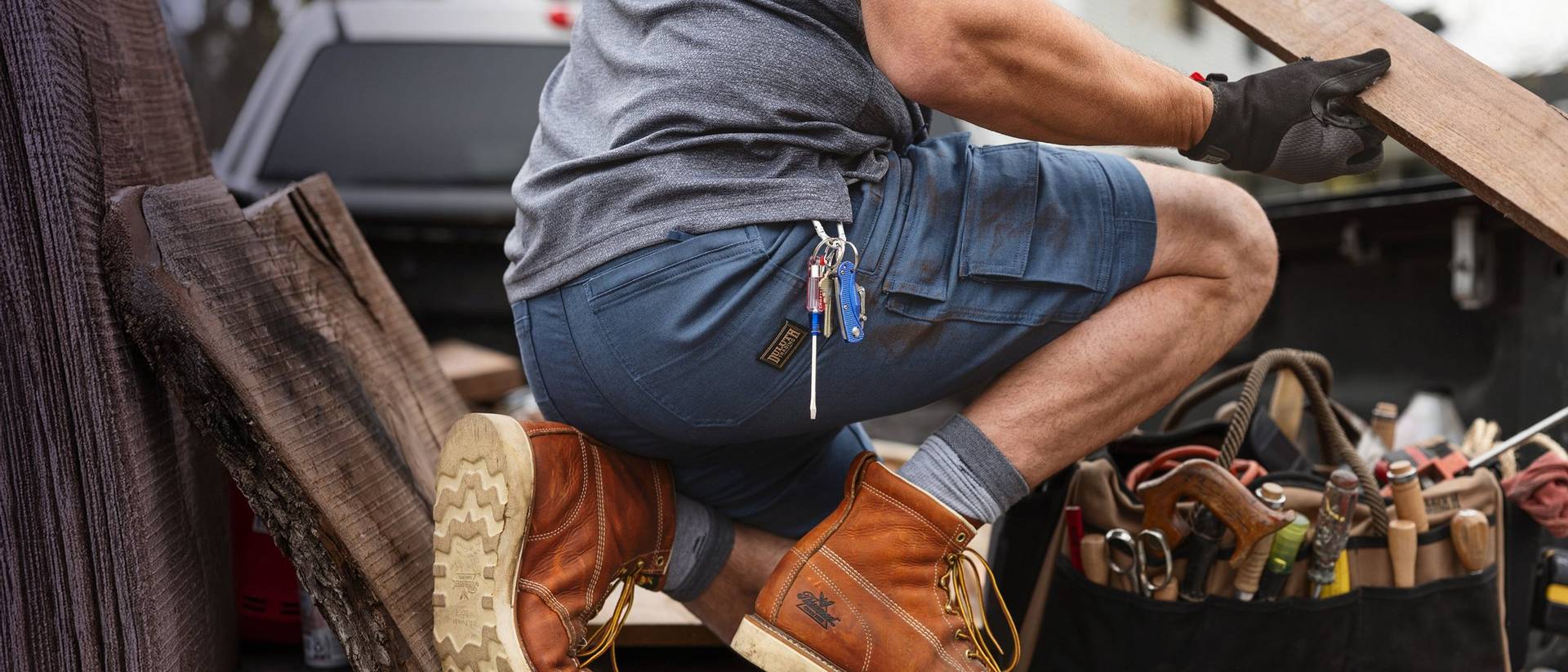 A man wearing shirts kneeling in the back of a pickup truck