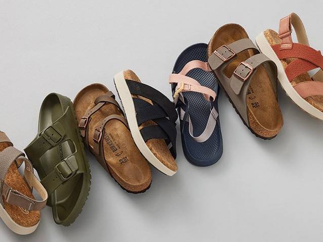stylized laydown of various women's sandals including Birkenstocks, Chacos, and Keen