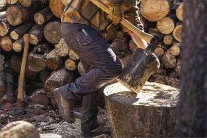 men wearing akhg stone run pants kneeling on a wood block; chopping wood