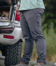 woman wearing grey akhg pants; standing in front of an SUV to go fish
