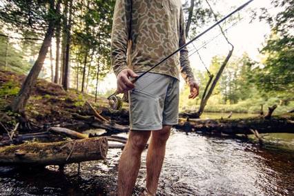 man holding a fishing pole standing in a stream