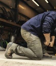 man crouching, changing a tire