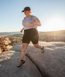 woman wearing shorts hiking on boulders in utah