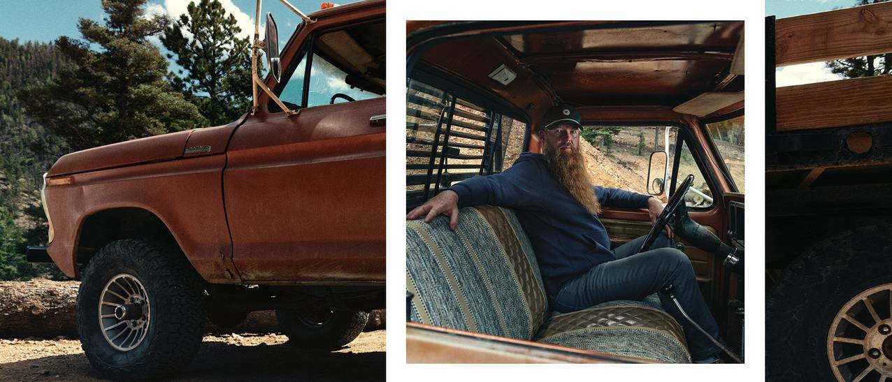 A man with a spectacular beard sits in the cab of a vintage truck. He is wearing a green Best Made hat, blue hooded sweatshirt and jeans. 