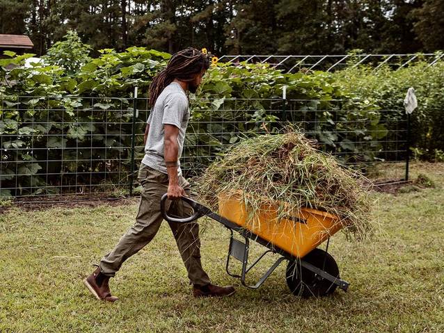 a man wearing dry on the fly pants, pushing a wheelbarrow on a vegetable farm