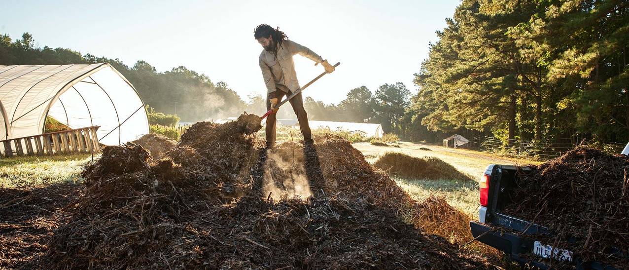 mark stands atop a huge compost pile, shoveling