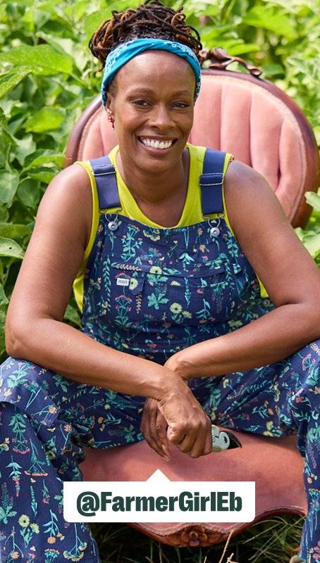 a women wearing navy blue overalls sits in a plush pink chair