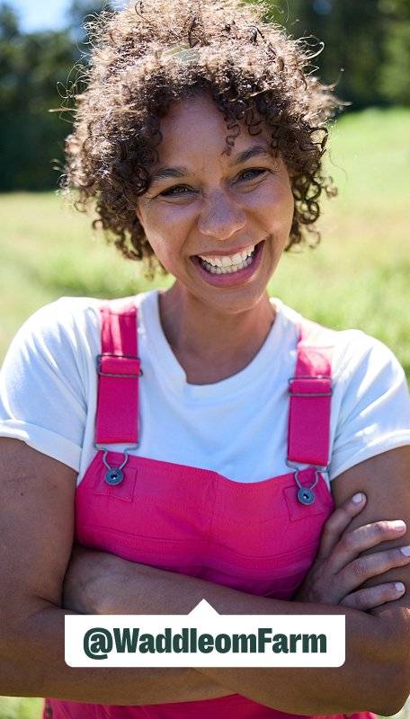 a women wearing hot pink overalls smiles while crossing her arms