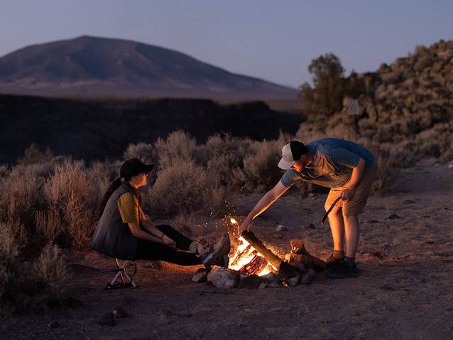 Two people sitting around a campfire