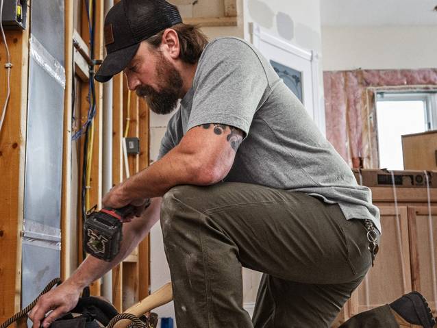 Man wearing a grey t-shirt, crouching.