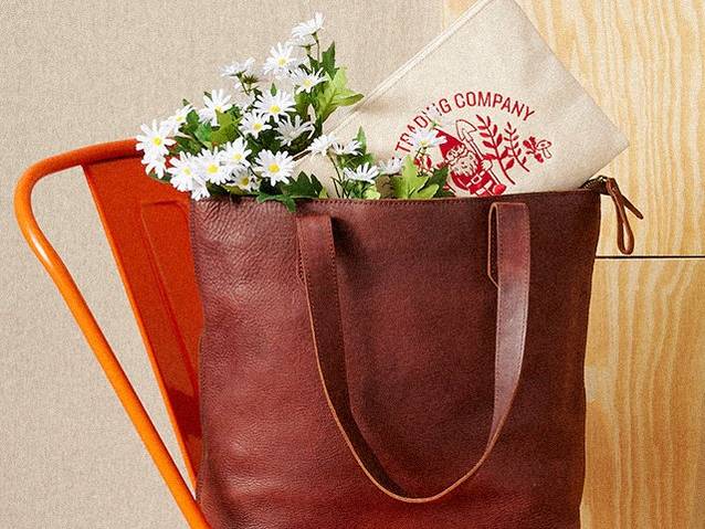 Lifetime Leather tote on orange chair with daisies and a duluth trading pouch sticking out