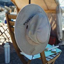 men's crusher hat hanging on the back of a chair